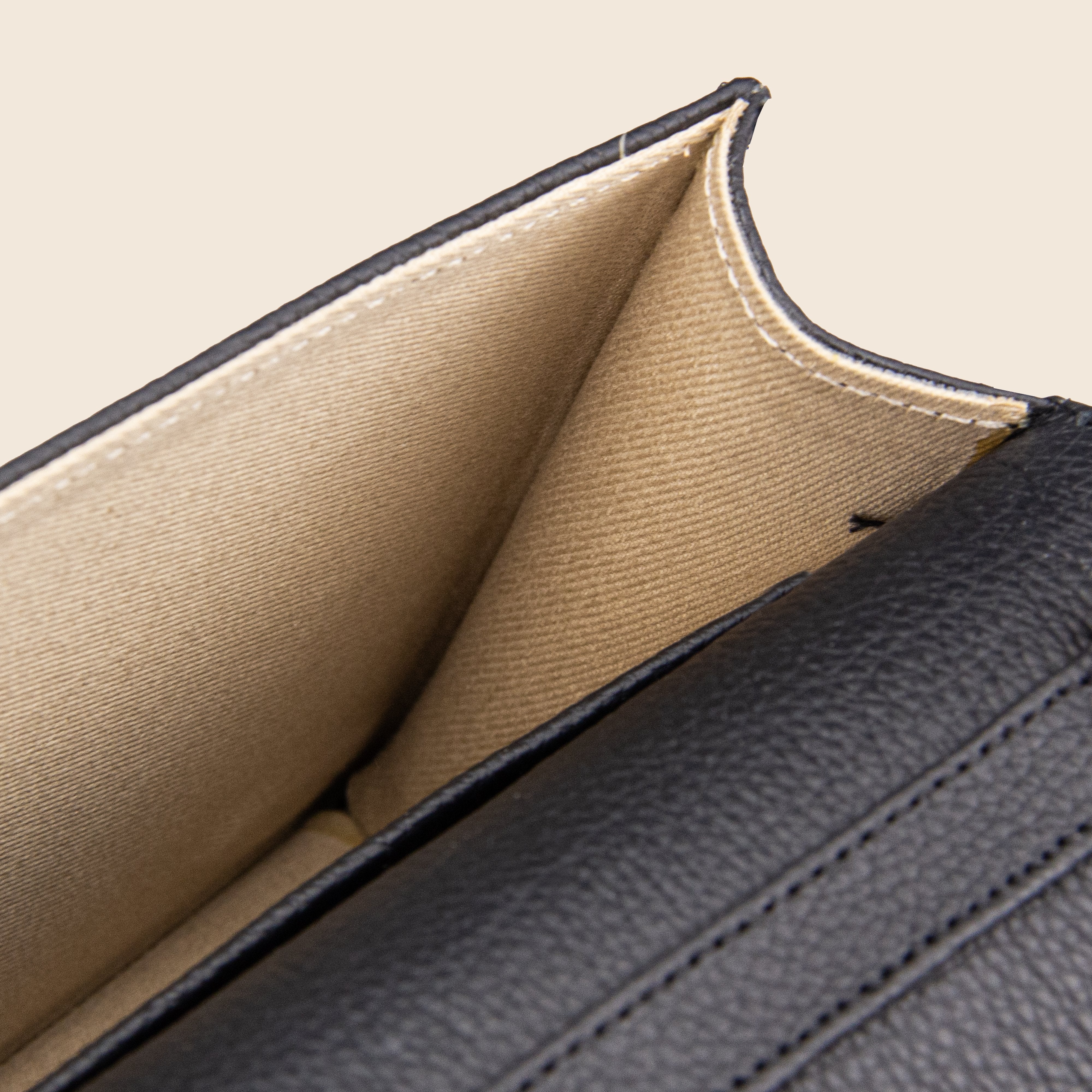 Close-up of the Vera in leather - Classic Black clutch, featuring a beige fabric lining and stitched edges inside—an elegant women’s bag crafted for style and sophistication.