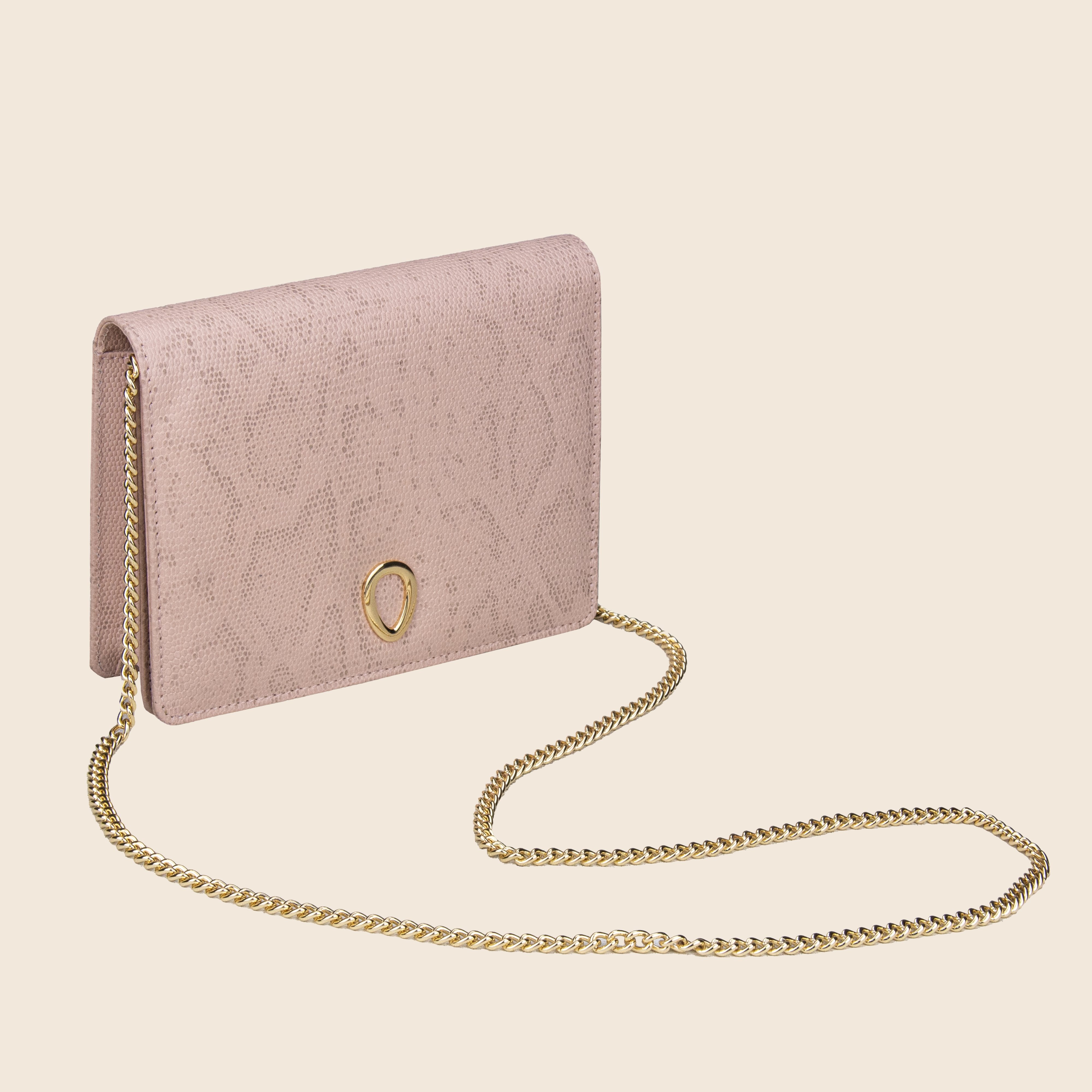 The Vera in leather - Python Rose is a pink textured women's clutch bag with a gold emblem and long gold chain strap, crafted from genuine leather and shown against a plain beige background.