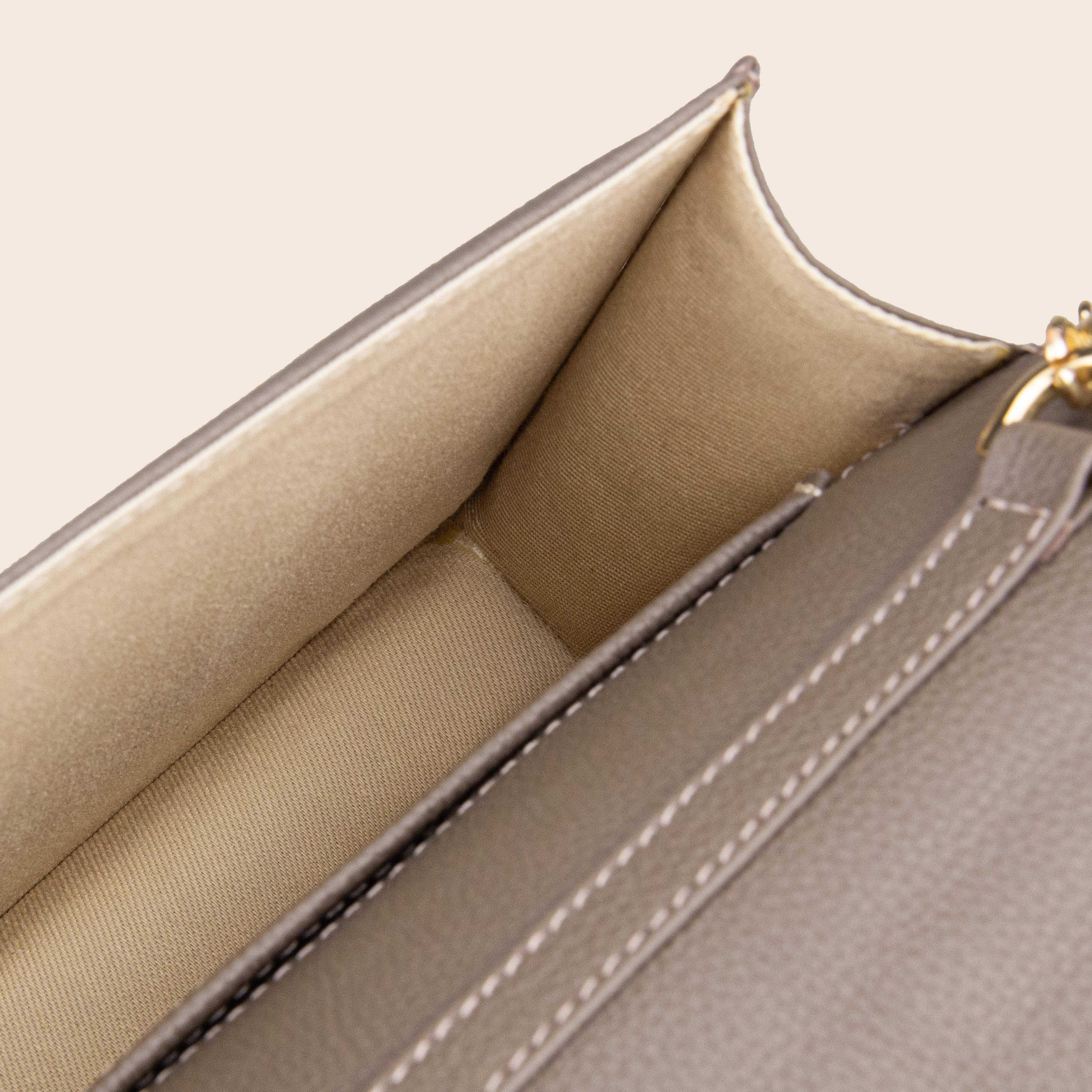 Close-up of the interior of Vera in leather - Stone Taupe, featuring two beige fabric-lined compartments and detailed edge stitching.
