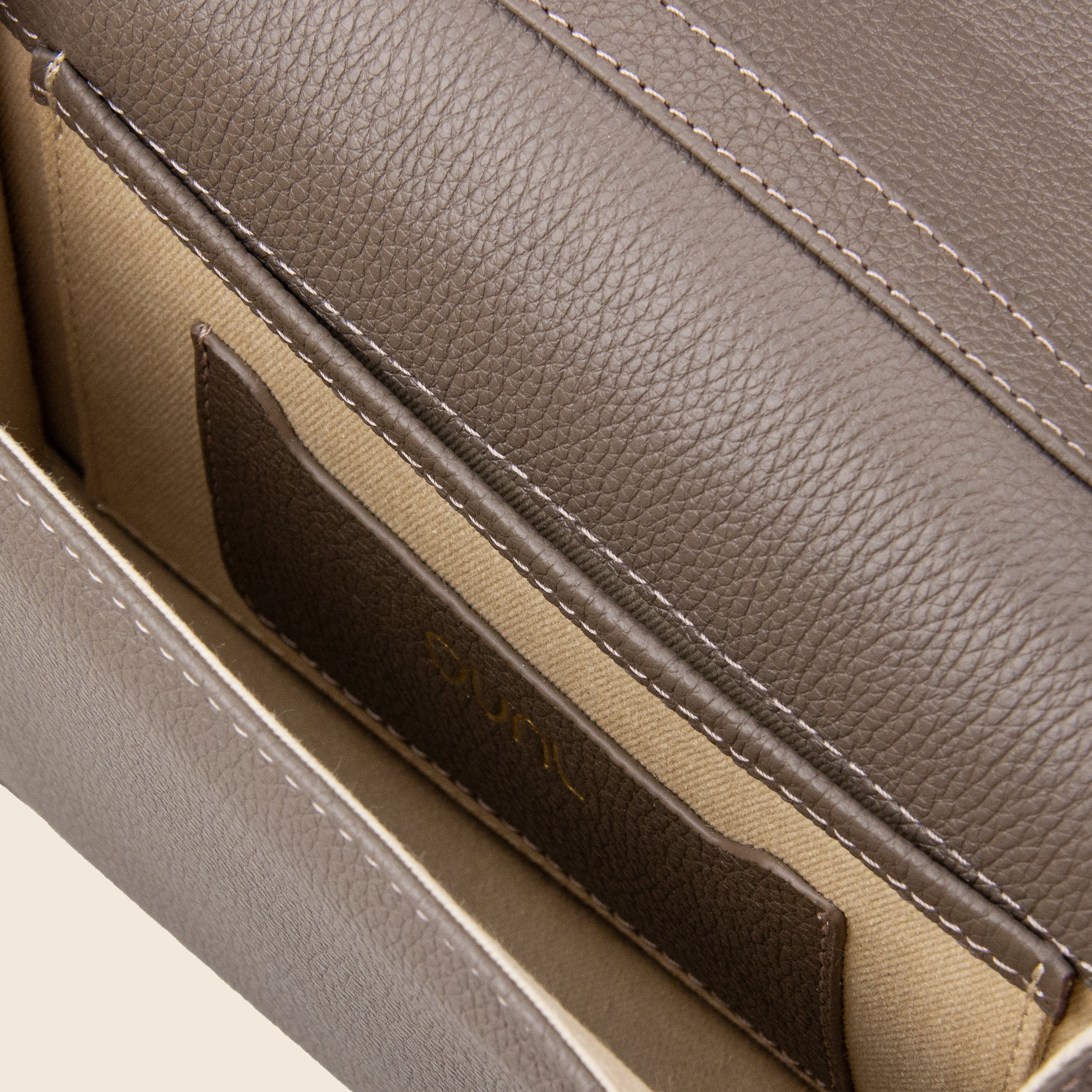 Close-up of the interior of Vera in leather - Stone Taupe, featuring beige fabric lining, visible stitching, and an inner pocket holding a brown leather cardholder.