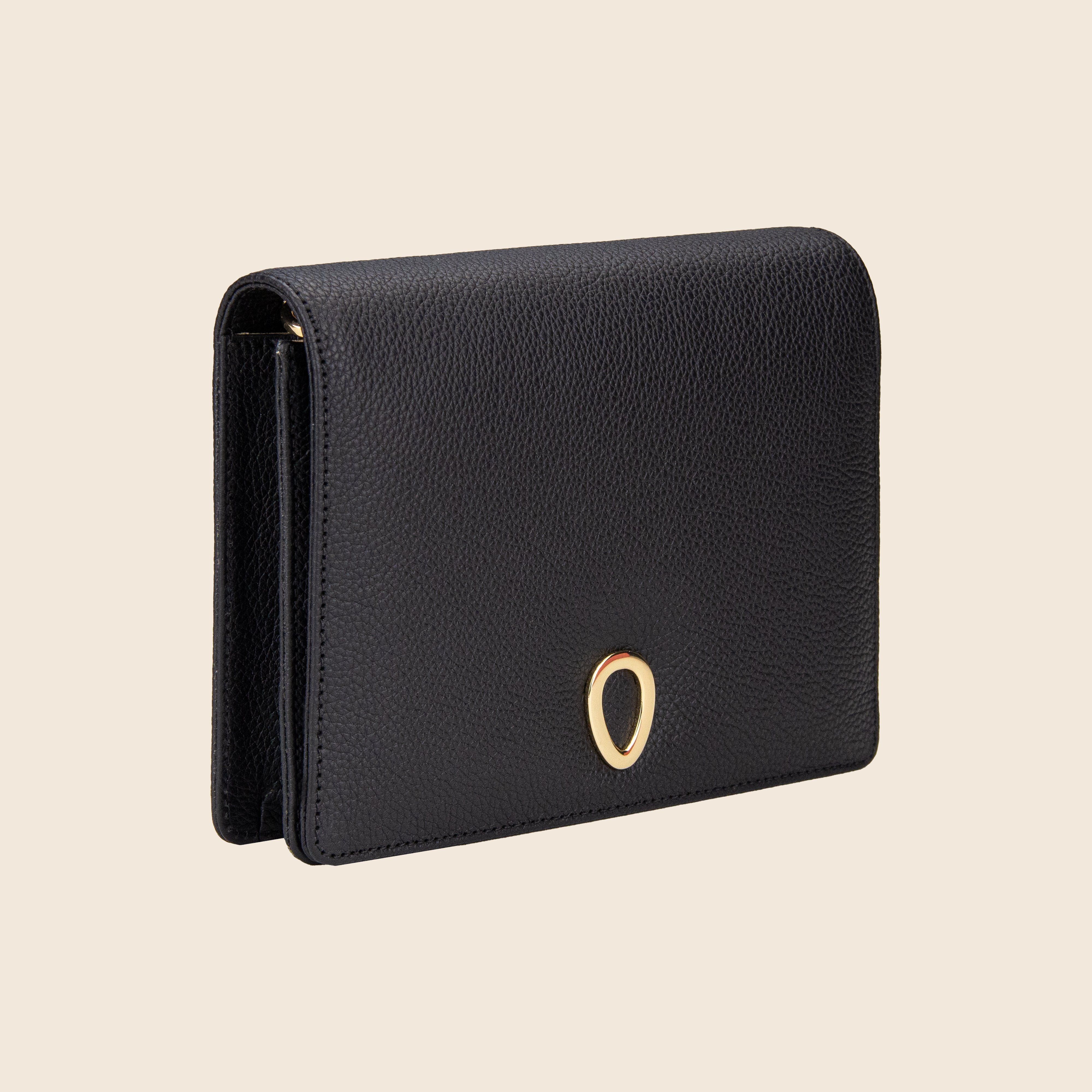 Vera in leather - Classic Black: a black textured leather clutch with a gold oval accent on the front, shown against a light beige background—an elegant women’s bag ideal for any occasion.